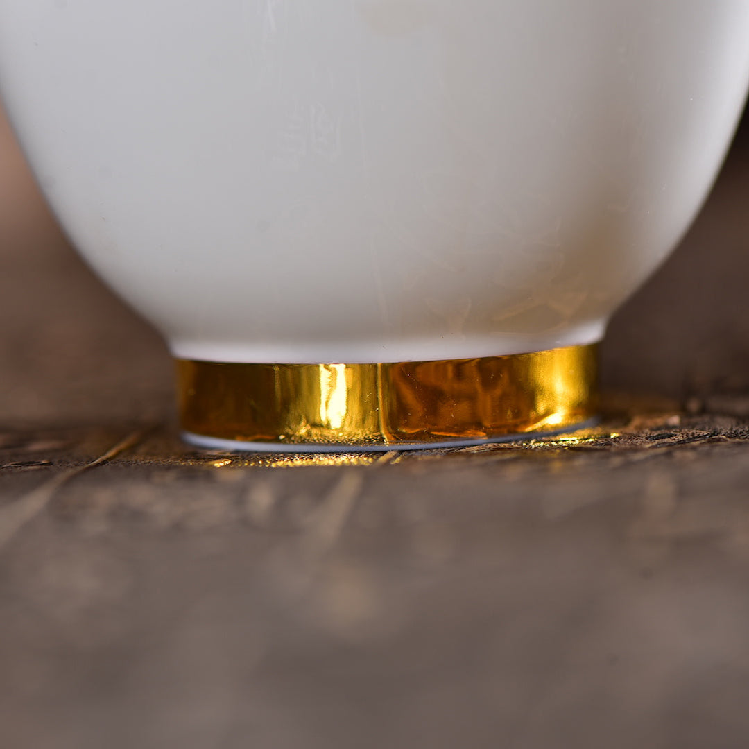 Close-up of the gold-trimmed base on a Dehua jade porcelain gaiwan