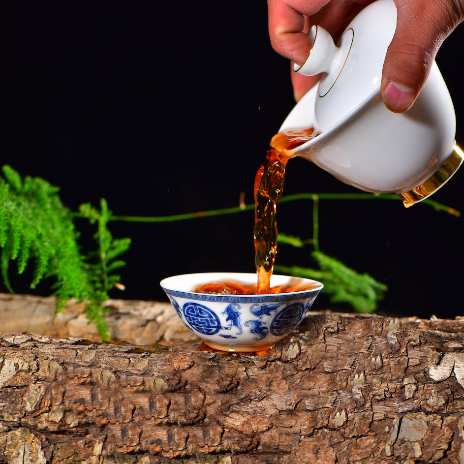 Gold on white Dehua jade porcelain gaiwan pouring tea into a cup
