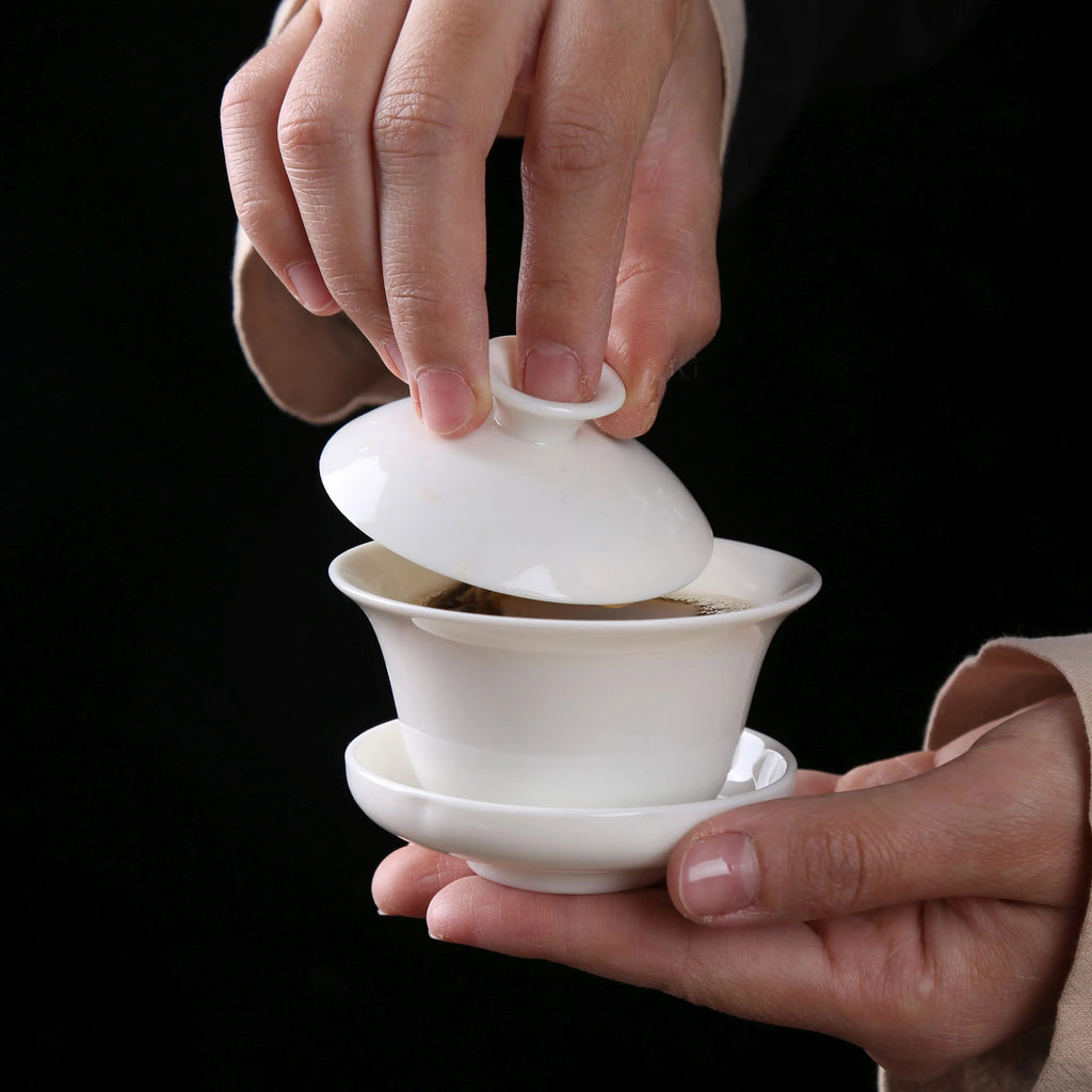 White porcelain gaiwan with lid lifted during gongfu tea brewing